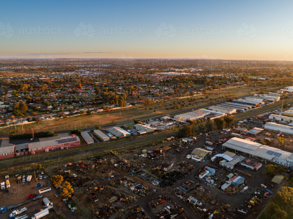 Train line passing sheds in industrial area in Dubbo at sunset seen from aerial perspective - Australian Stock Image