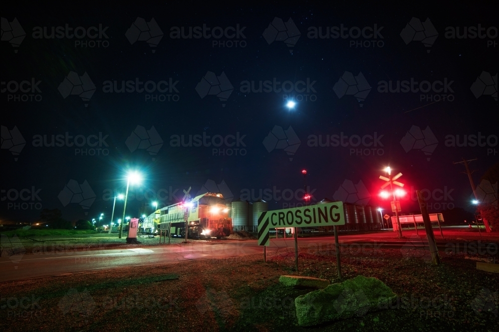 Train passing rail crossing at night. - Australian Stock Image