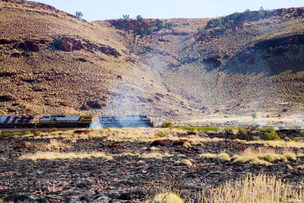 Train passing through burnt landscape - Australian Stock Image
