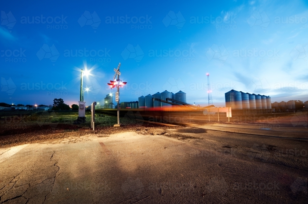 Train speeds by level crossing in the early morning light - Australian Stock Image