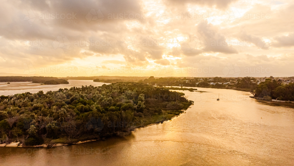 tranquil river estuary winding through vibrant green landscape at golden hour - Australian Stock Image