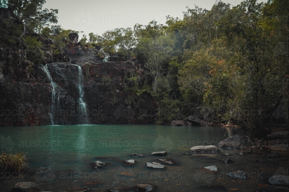 Tranquil waterhole with cascading waterfall at Cedar Creek Falls in the Whitsundays - Australian Stock Image