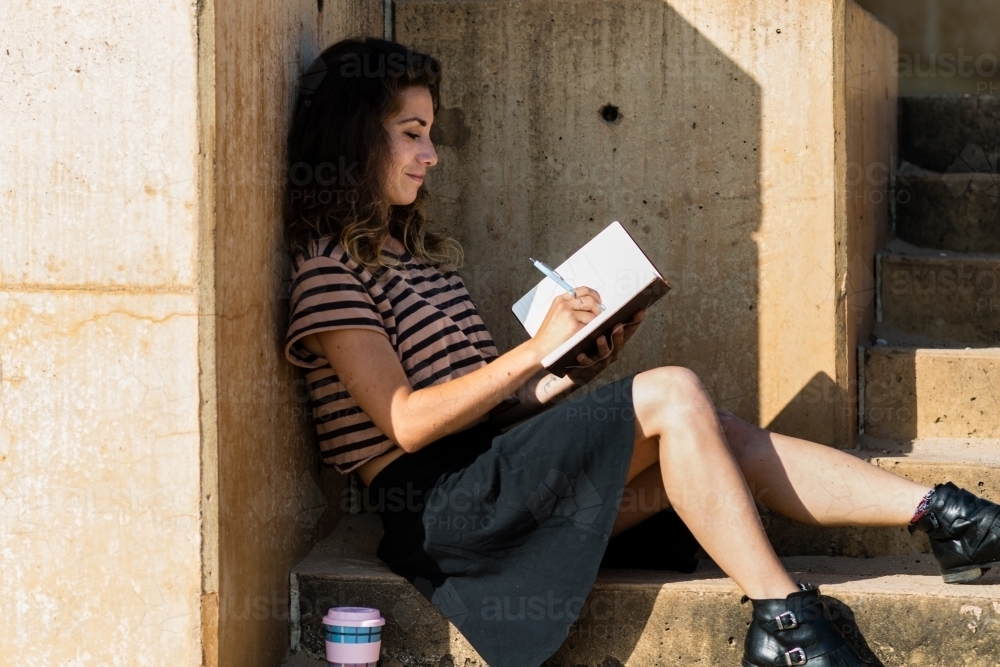 traveller writing in diary by the ocean - Australian Stock Image