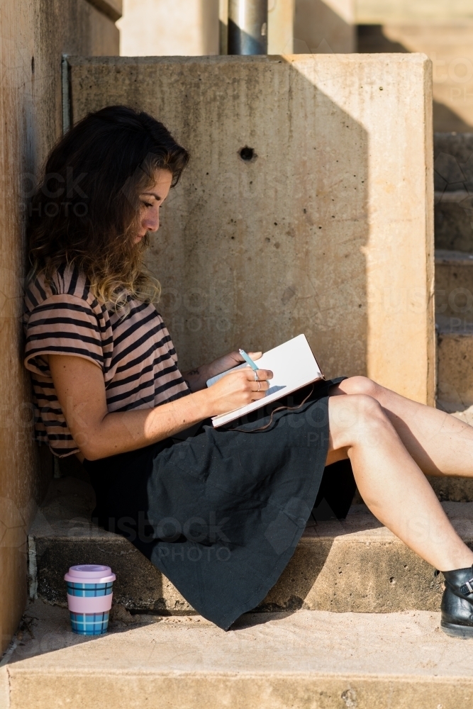 traveller writing in diary by the ocean - Australian Stock Image