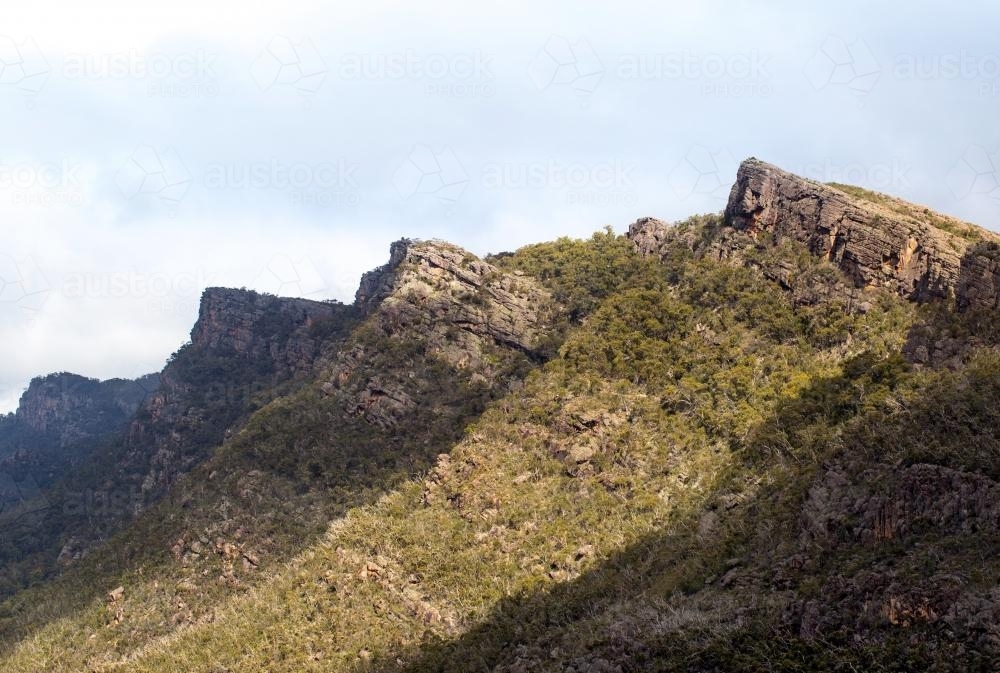 Tree covered sharp peaked Grampian Mountains in sunlight and shade - Australian Stock Image