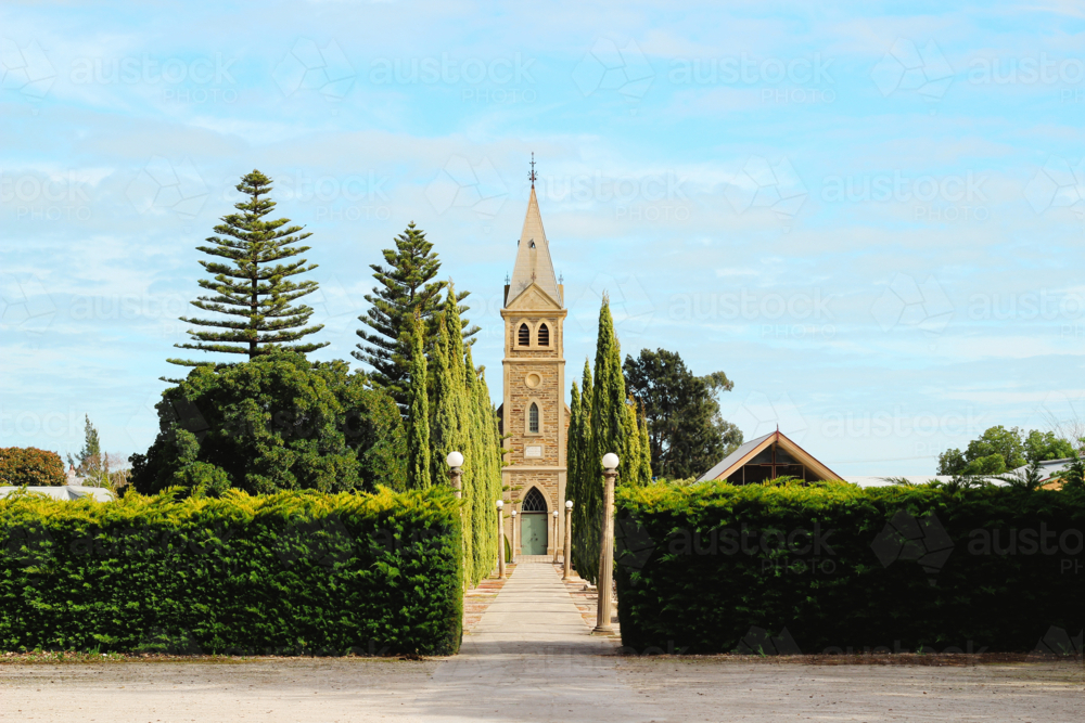 Tree‑lined path leading to a historic church under a bright, open sky - Australian Stock Image