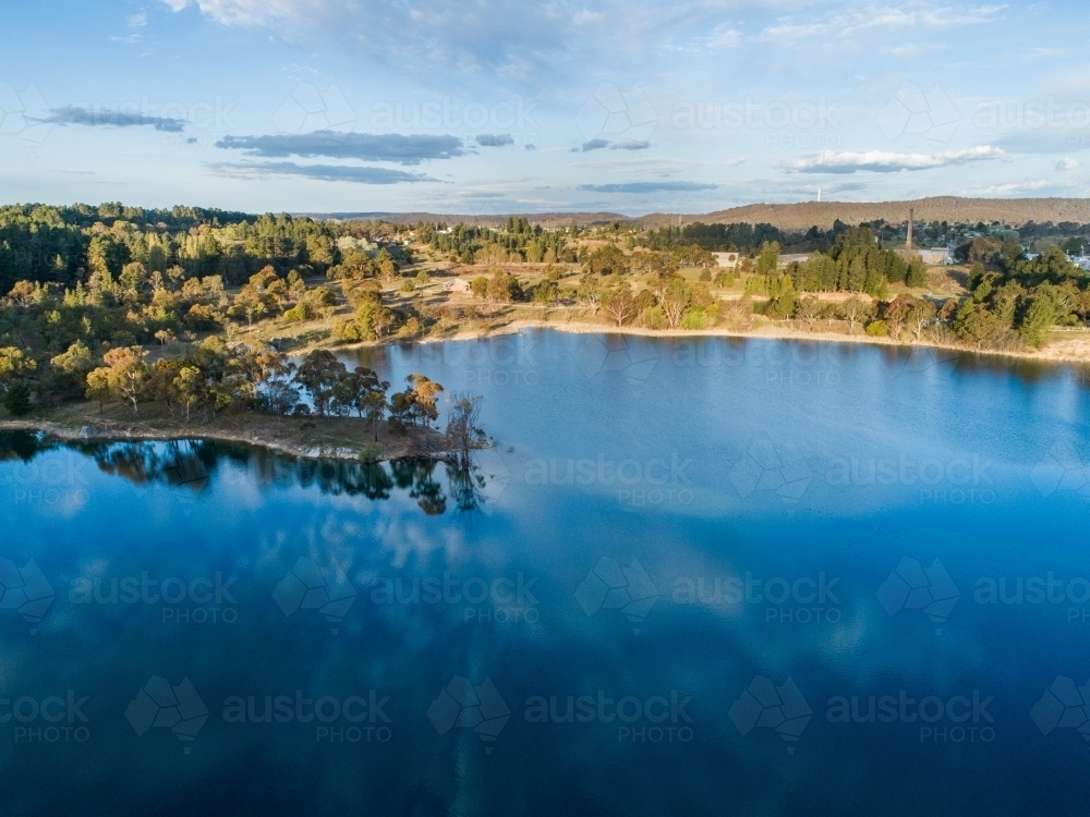 Image of Trees at lakes edge reflecting in blue water of old quarry ...