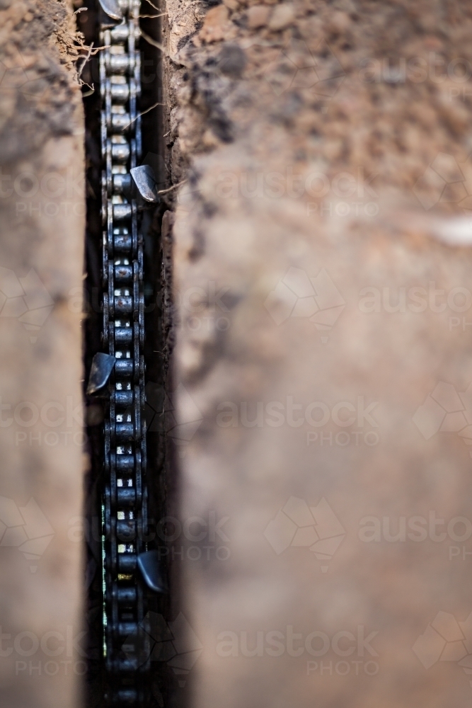 Trencher chain blade digging hole in dirt - Australian Stock Image