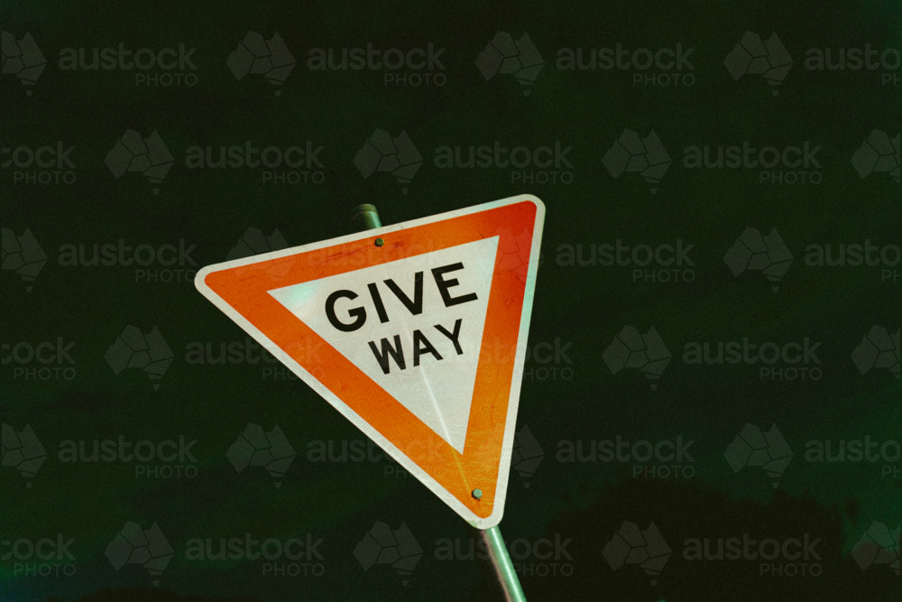 Triangular “Give Way” road sign stands against the dark - Australian Stock Image