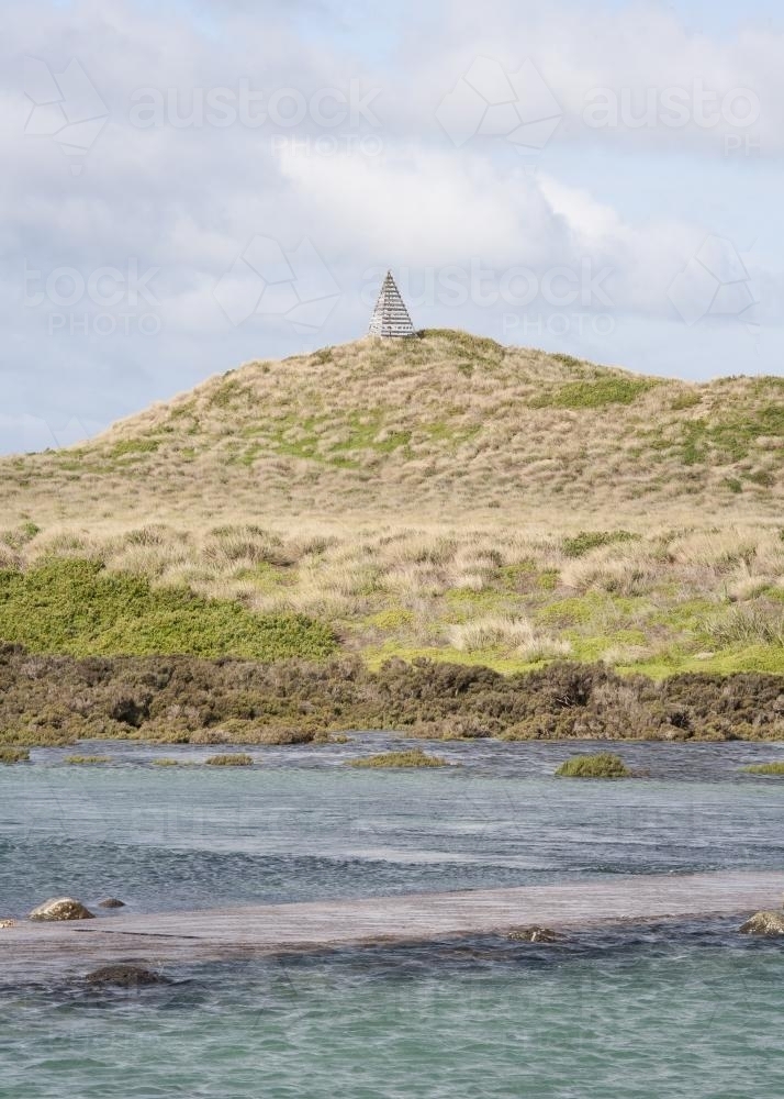 Trig point on hill seen from the sea - Australian Stock Image
