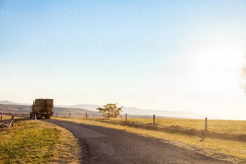 Truck carrying hay along rural country road with copy space - Australian Stock Image