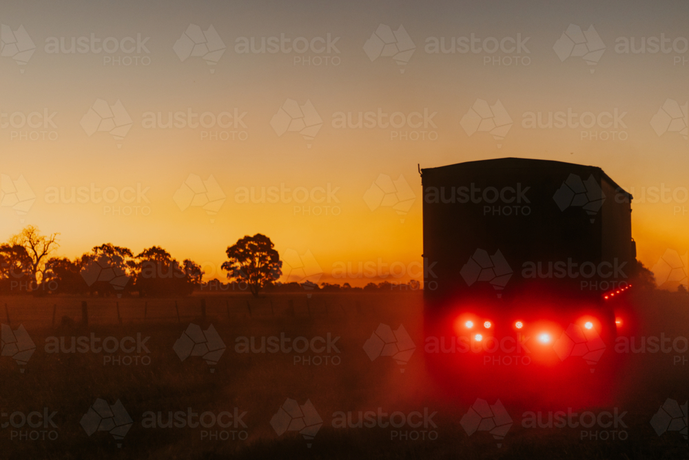Truck driving into dusty sunset - Australian Stock Image