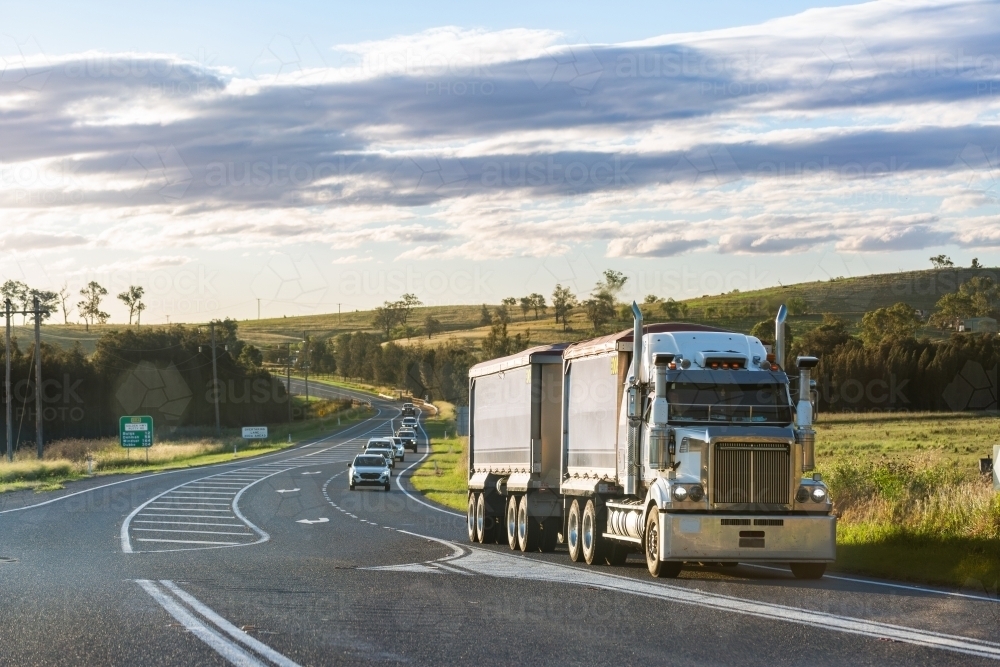 Truck driving on rural road in country followed by cars of mine shift workers heading home - Australian Stock Image