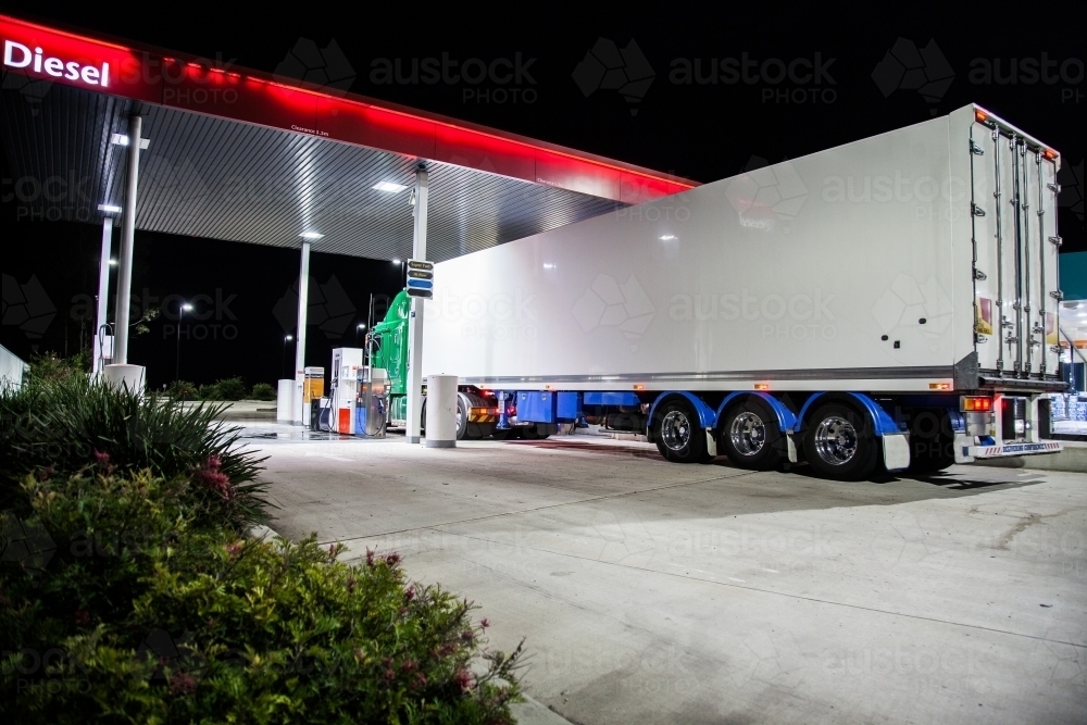 Truck filling up with Diesel petrol at service station at night - Australian Stock Image