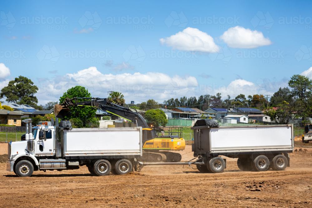 truck hauling dirt on construction site with earthmoving machinery - Australian Stock Image