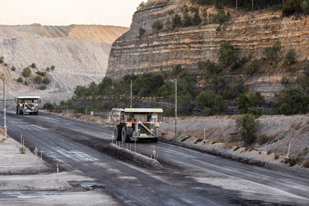 Trucks working late in the day on open cut coal mining extraction site - Australian Stock Image