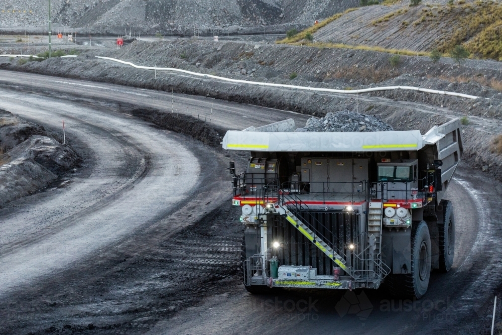 Trucks working late in the day on open cut coal mining extraction site - Australian Stock Image