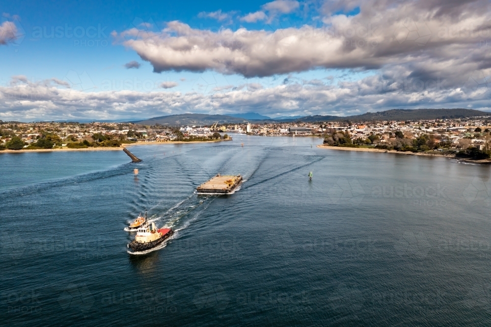 Tug boat towing salvage barge out to sea with pilot boat alongside - Australian Stock Image