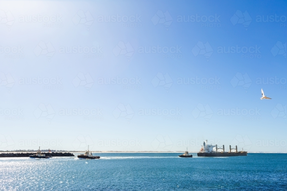 Tug boats leaving ship to sail out into ocean from Australian port - Australian Stock Image