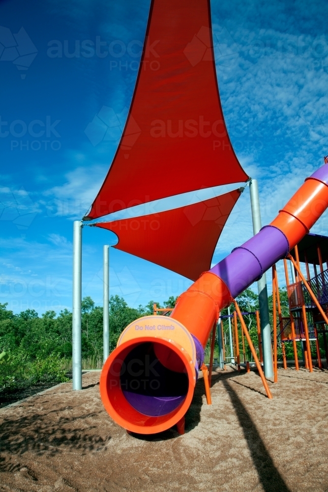 Tunnel slide with red shade sail at playground - Australian Stock Image