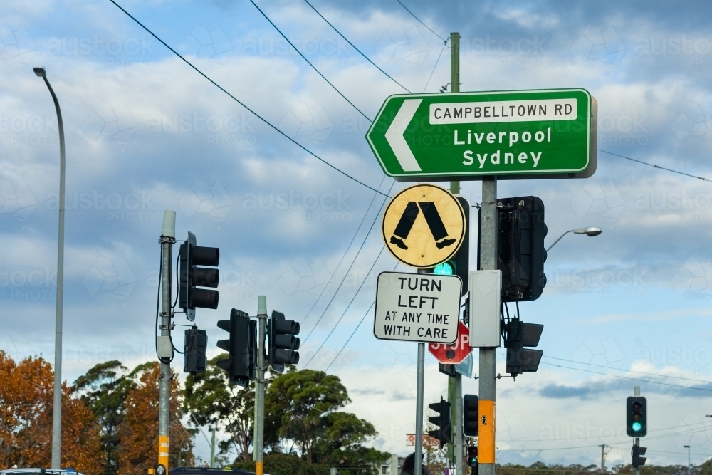 turn left at any time with care and pedestrian crossing sign at traffic lights with directions - Australian Stock Image