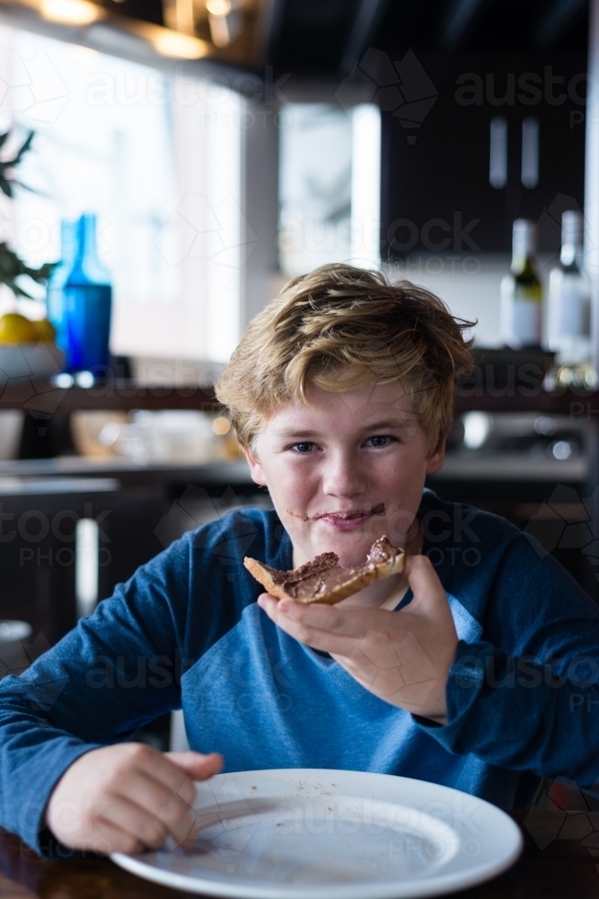 tween boy enjoying toast and milk for breakfast - Australian Stock Image