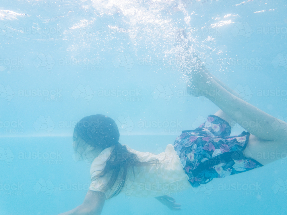 Tween child swimming underwater in backyard pool water in summer - Australian Stock Image