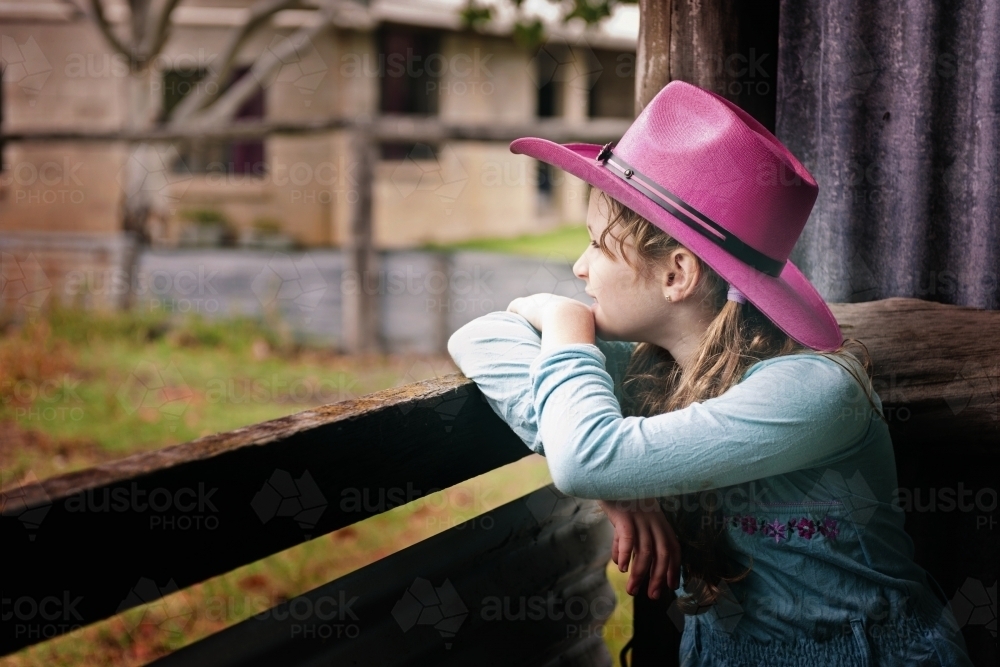 Tween cowgirl looking out from a shed - Australian Stock Image