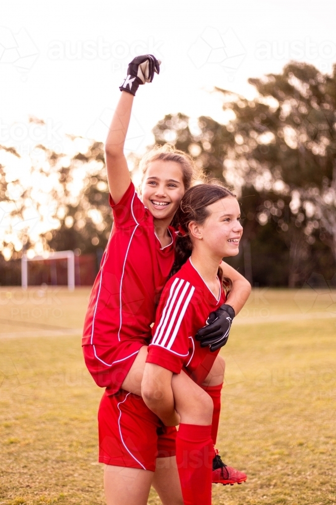 Tween female soccer player celebrating victory with her team-mate - Australian Stock Image