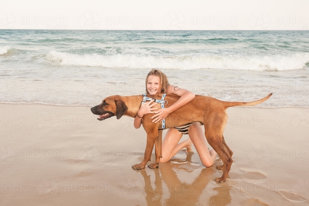 Tween girl at a dog friendly beach with her dog - Australian Stock Image