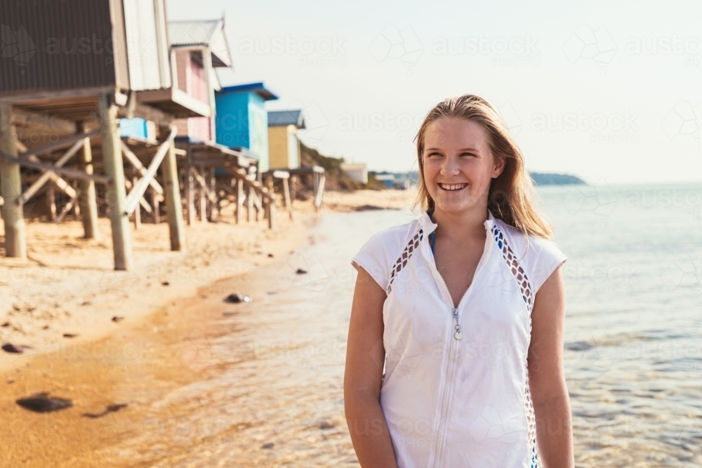 Tween girl at the beach wearing a white short sleeve rashie - Australian Stock Image