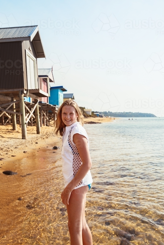 Tween girl at the beach wearing a white short sleeve rashie - Australian Stock Image