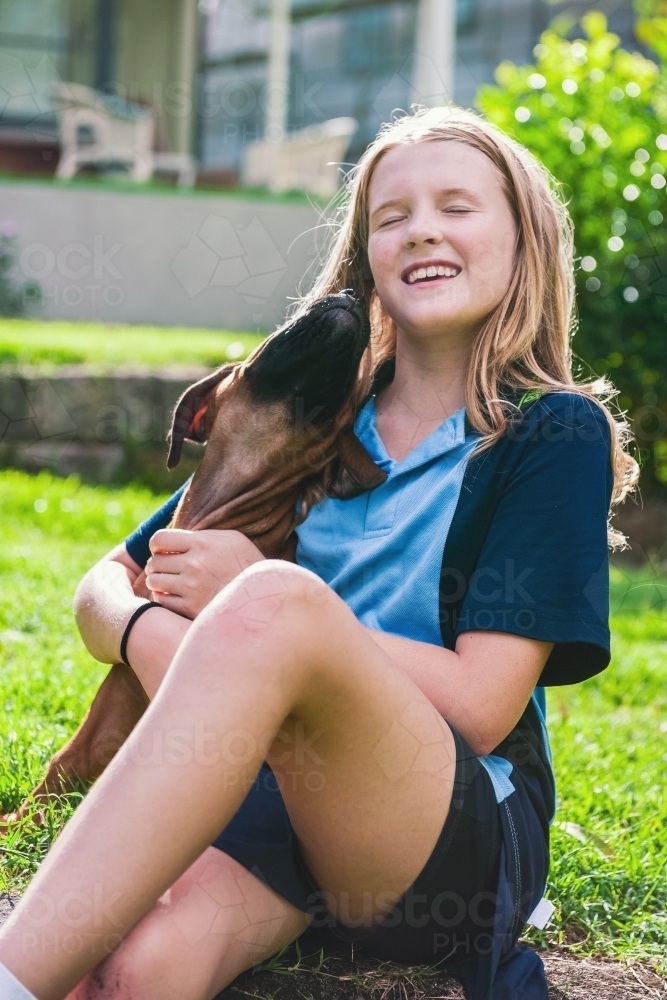 Tween girl being kissed by her new puppy - Australian Stock Image