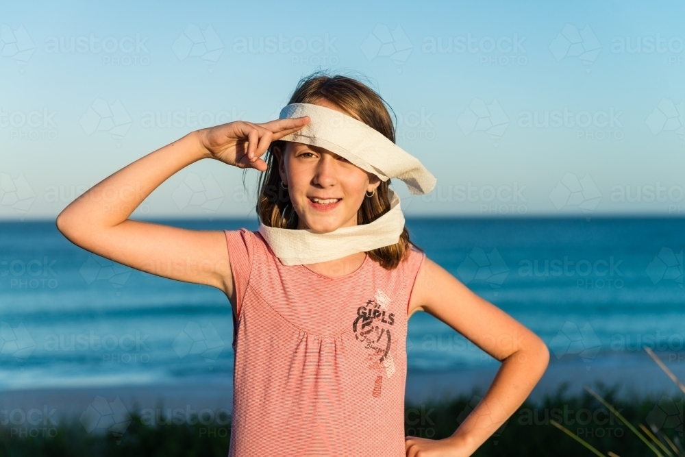 tween girl being silly, making an eye patch with toilet paper, and saluting - Australian Stock Image