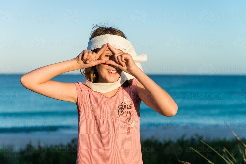 tween girl being silly, making an scarf with toilet paper, and doing an spooky symbol - Australian Stock Image