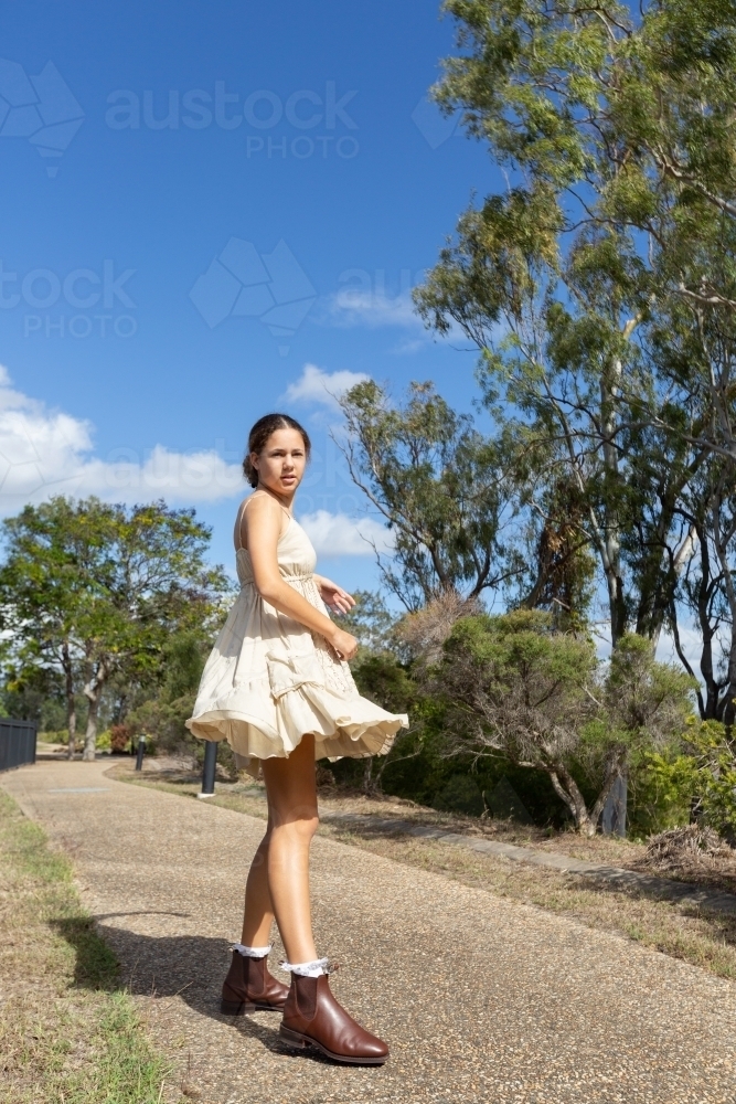 tween girl in short dress and boots on path - Australian Stock Image