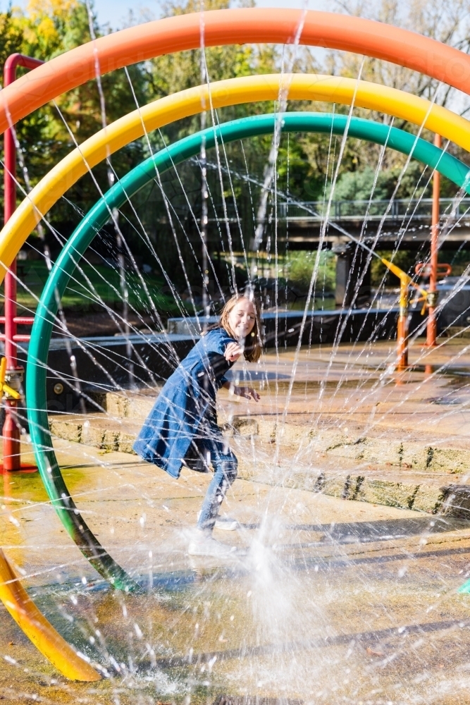 tween girl playing in an outdoor park with fountain - Australian Stock Image