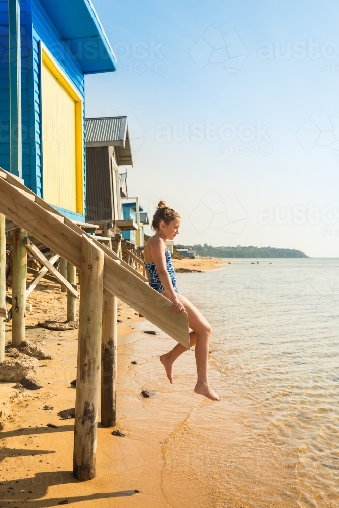 Tween girl sitting on stairs at a beach box, Mt Martha - Australian Stock Image