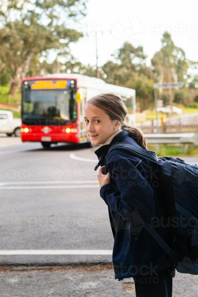 tween girl standing on the roadside catching the bus to school - Australian Stock Image