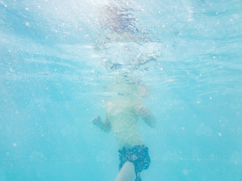 Tween girl swimming underwater in backyard pool water in summer - Australian Stock Image