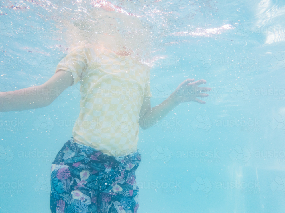 Tween girl swimming underwater in backyard pool water in summer - Australian Stock Image