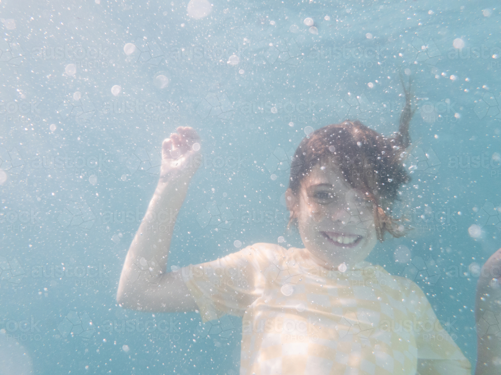 Tween girl swimming underwater in backyard pool water in summer - Australian Stock Image