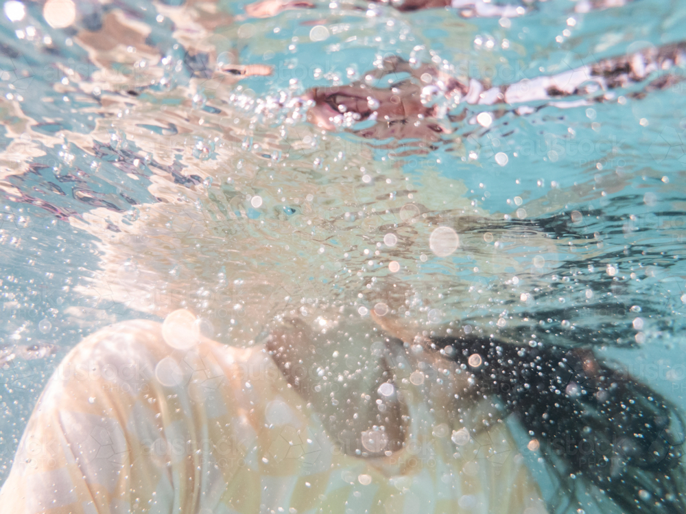 Tween girl swimming underwater in backyard pool water in summer - Australian Stock Image