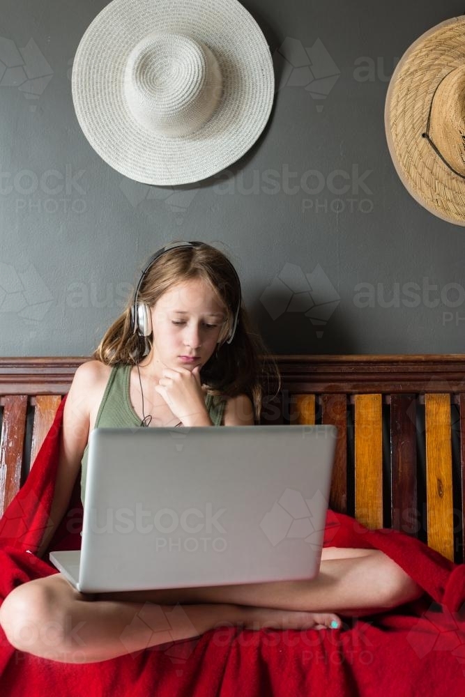 tween girl using a laptop, with headphones - Australian Stock Image