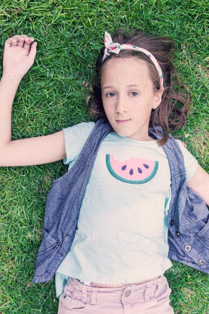 tween girl with watermelon t-shirt lying on the grass - Australian Stock Image