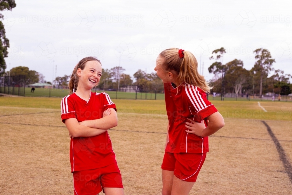 Tween girls from the same football team laughing together - Australian Stock Image