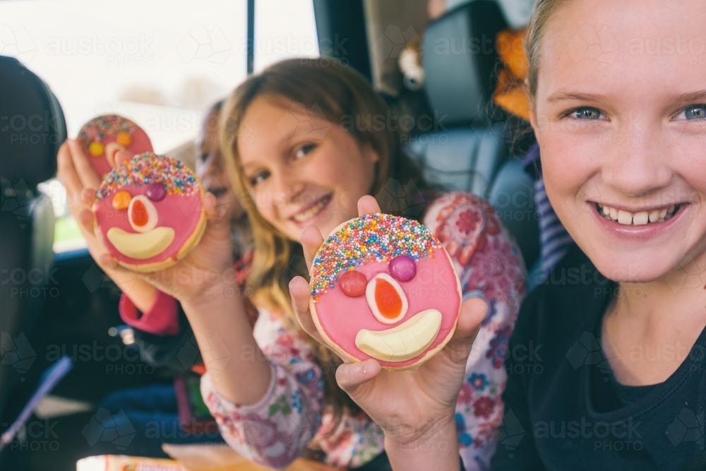 Tween girls on a road trip, holding a sweet treat from a cafe - Australian Stock Image