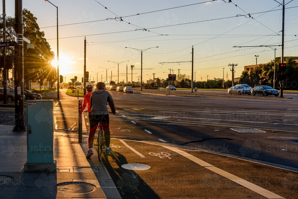 Twilight street shot, two cyclists waiting on traffic light at intersection - Australian Stock Image