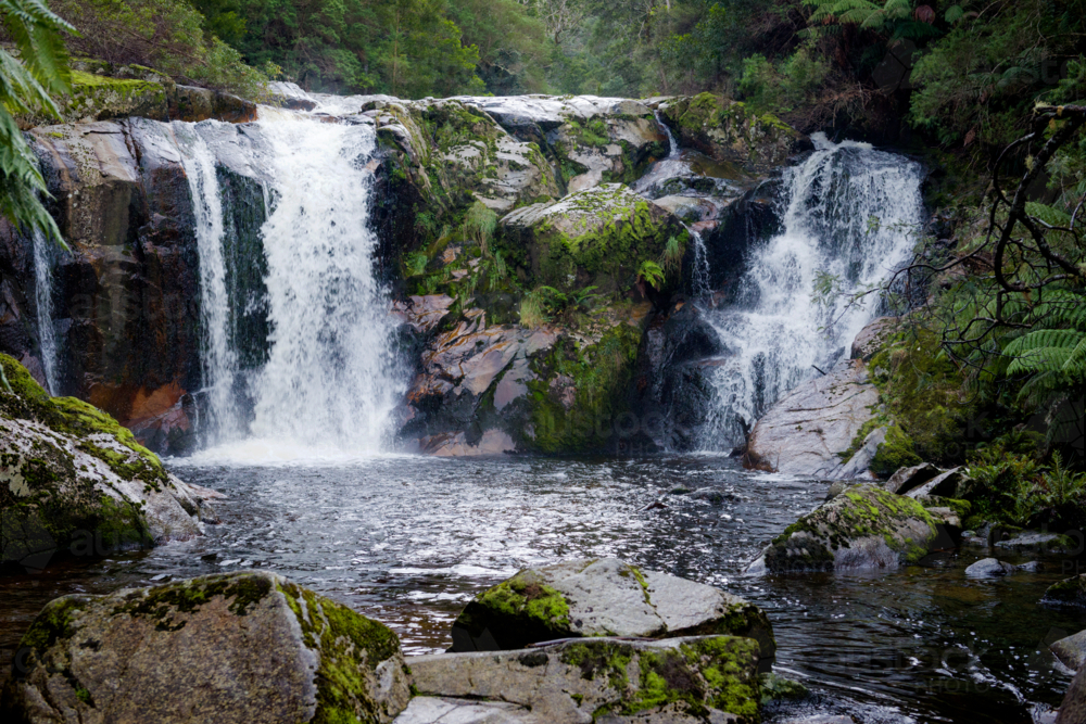 Image of Twin waterfall cascading over mossy rocks into a tranquil ...