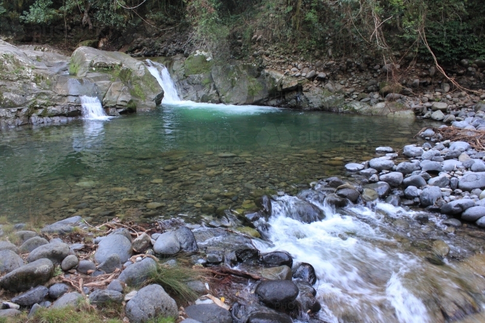 Twin waterfalls flowing into pool and over rocks - Australian Stock Image